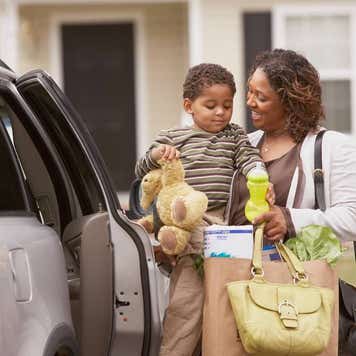 a mom opening the door to sit down her son in his car seat