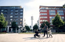 A father with two young children walking in front of condo buildings in the city