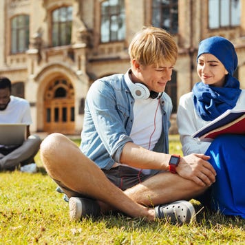 Two college students study on college campus lawn