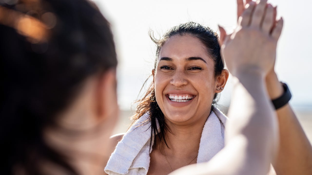 Smiling woman giving high five to her friend after exercising