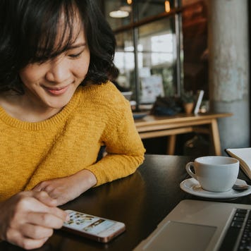 A young woman researches on her phone at a cafe.