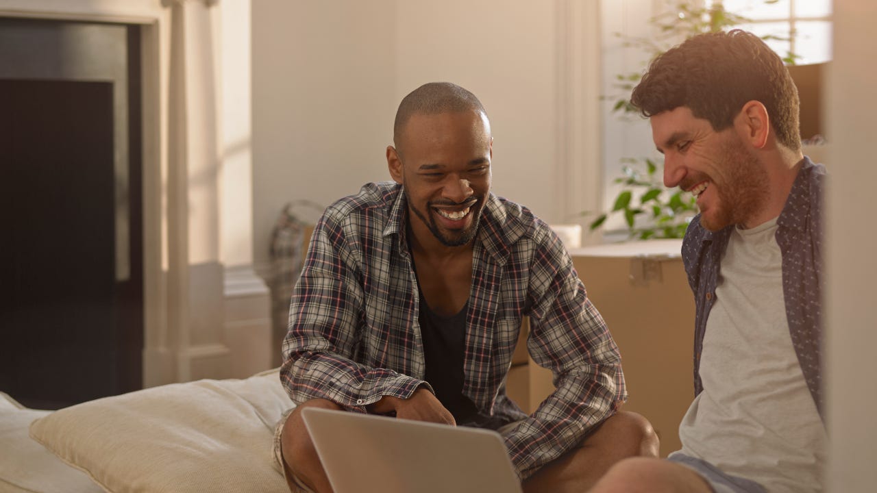 Two men in their new home looking at a laptop