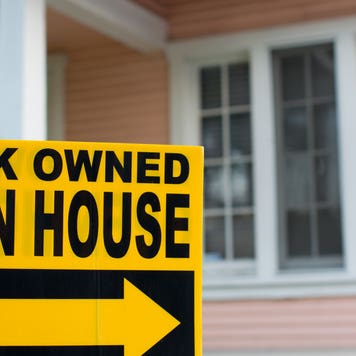 A closeup of a bank-owned open house sign