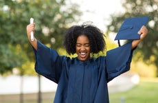 Woman holds up diploma at graduation