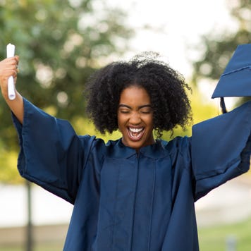 Woman holds up diploma at graduation