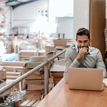 manager working on a laptop in a warehouse