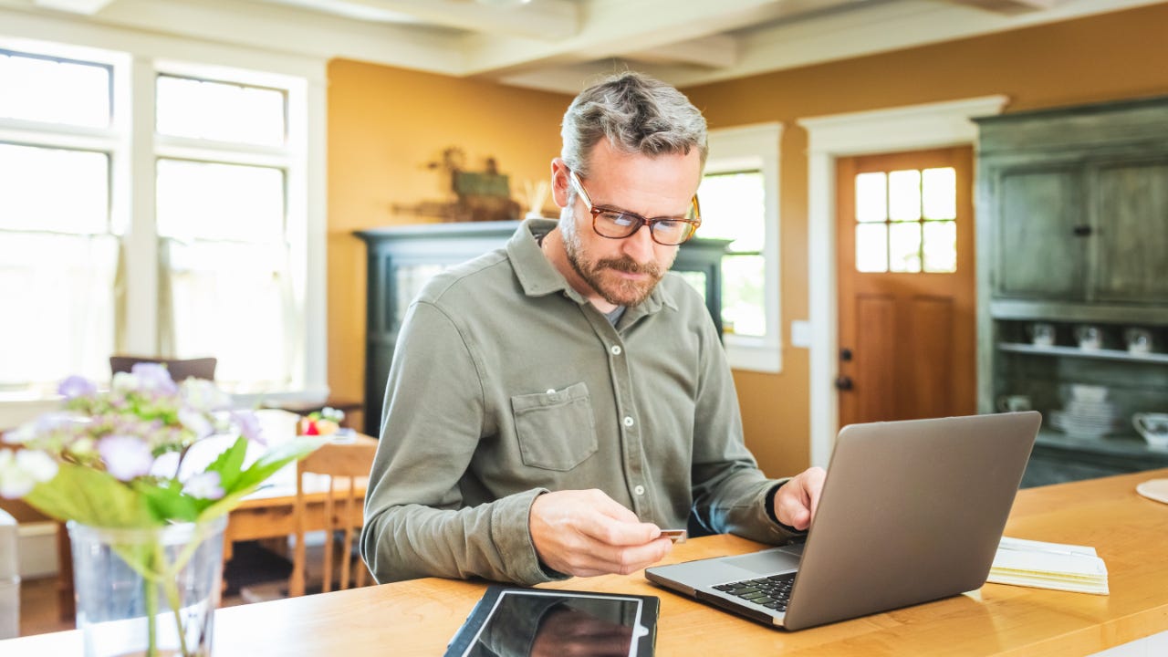 Person sitting at computer while holding a credit card