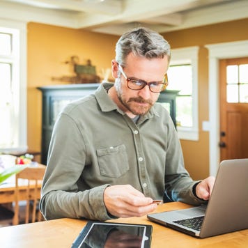 Person sitting at computer while holding a credit card