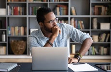 A man at his desk stares out the window thoughtfully