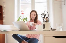 Full length of young woman examining financial bill while working from home