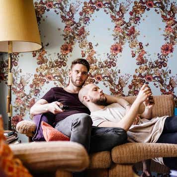 A gay couple relaxing while watching tv at home with each other