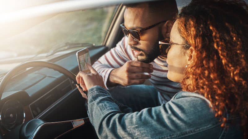 couple looking at mobile phone in car
