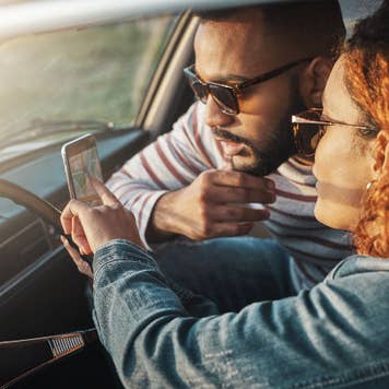 couple looking at mobile phone in car