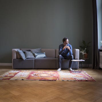 Man sitting on couch at home looking through window