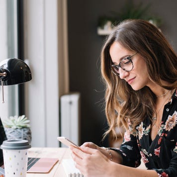 A woman looks at her phone at her desk