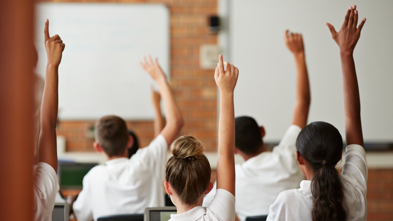 Students in a classroom raise their hands
