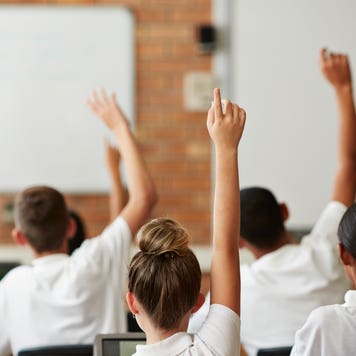 Students in a classroom raise their hands