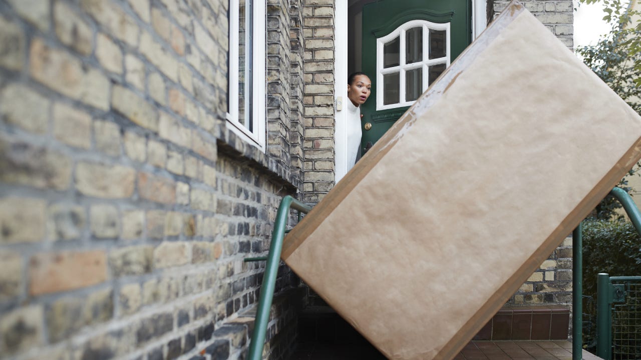 Woman looking at package at entrance of house