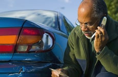 Man Using a Cell Phone Beside His Scratched Car
