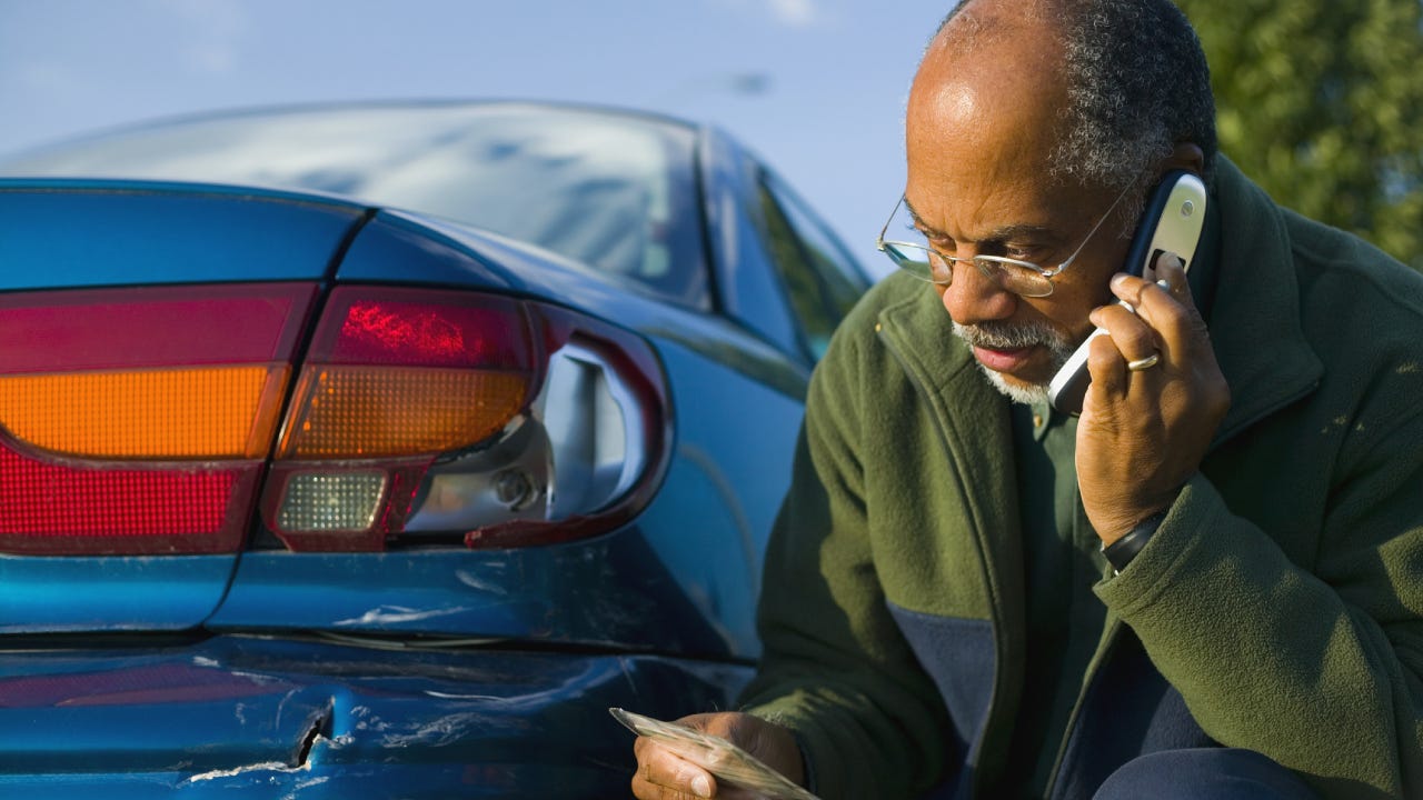 Man Using a Cell Phone Beside His Scratched Car