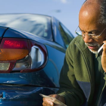 Man Using a Cell Phone Beside His Scratched Car