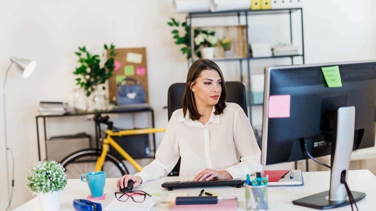 Young woman working in her office, typing on a desktop PC keyboard