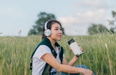 Young Woman Relaxing In Nature, Drinking With A Reusable Coffee Cup