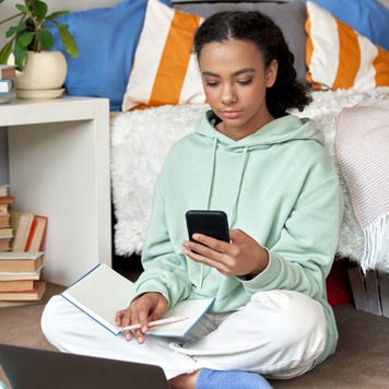 High school student sits on bedroom floor with a notebook