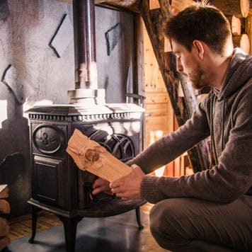 Young Man Putting Firewood in Wood Burning Stove