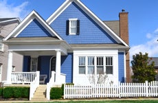 A blue single-family home with picket fence