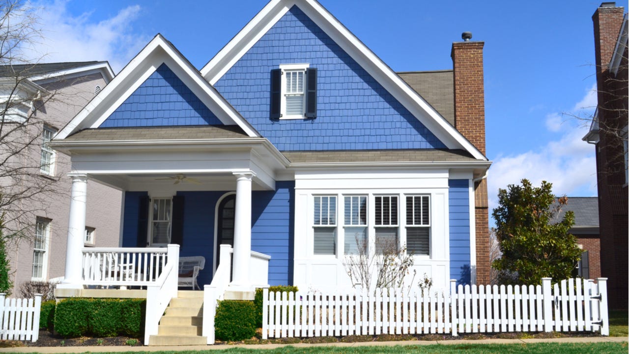 A blue single-family home with picket fence