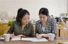 Two women go over paperwork in the kitchen