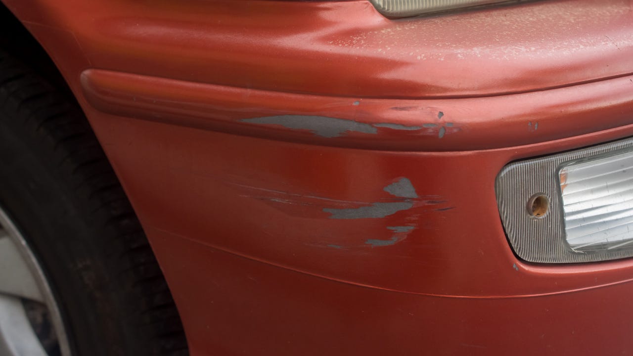 Red bumper car scratched with deep damage to the paint