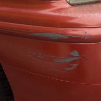 Red bumper car scratched with deep damage to the paint