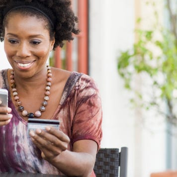 Person looking at their mobile phone and holding credit card
