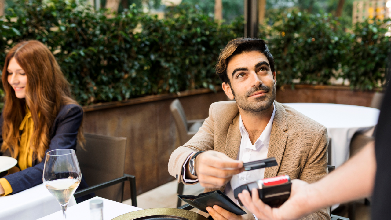 white man handing card to pay