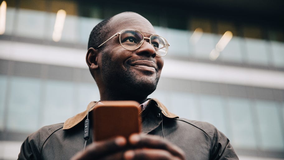 A businessman with a phone smiles and looks into the distance
