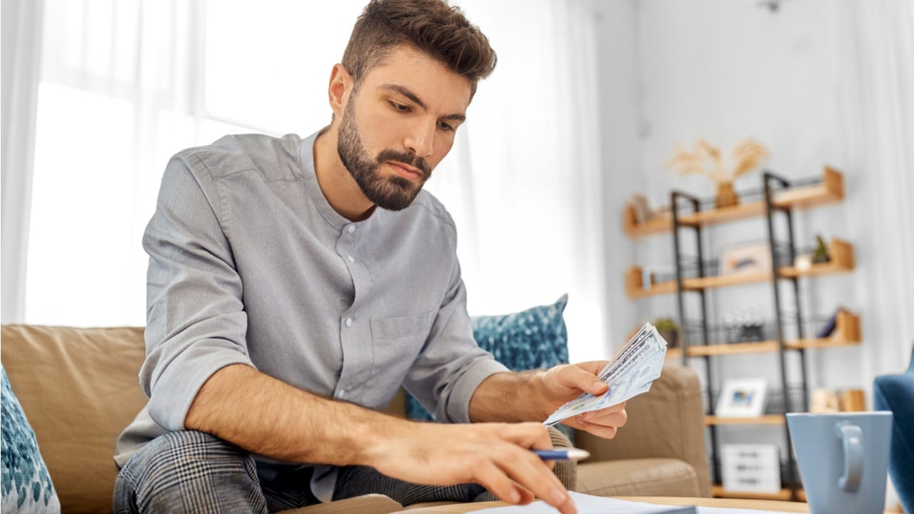 Man types on a calculator in his home