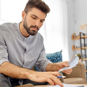 Man types on a calculator in his home