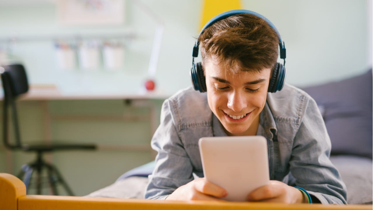 Teenager listens to music while using a tablet