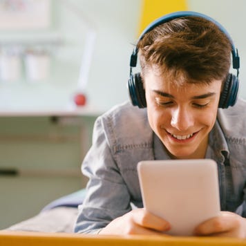 Teenager listens to music while using a tablet