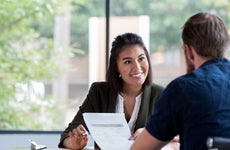 A smiling woman shows a document to a man.