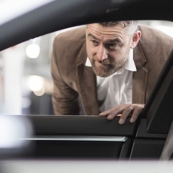 Man looking into car in car dealership