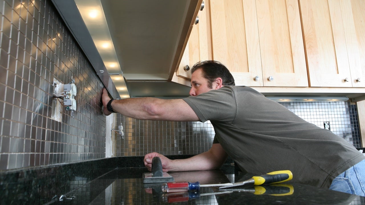 A contractor installs backsplash in a kitchen