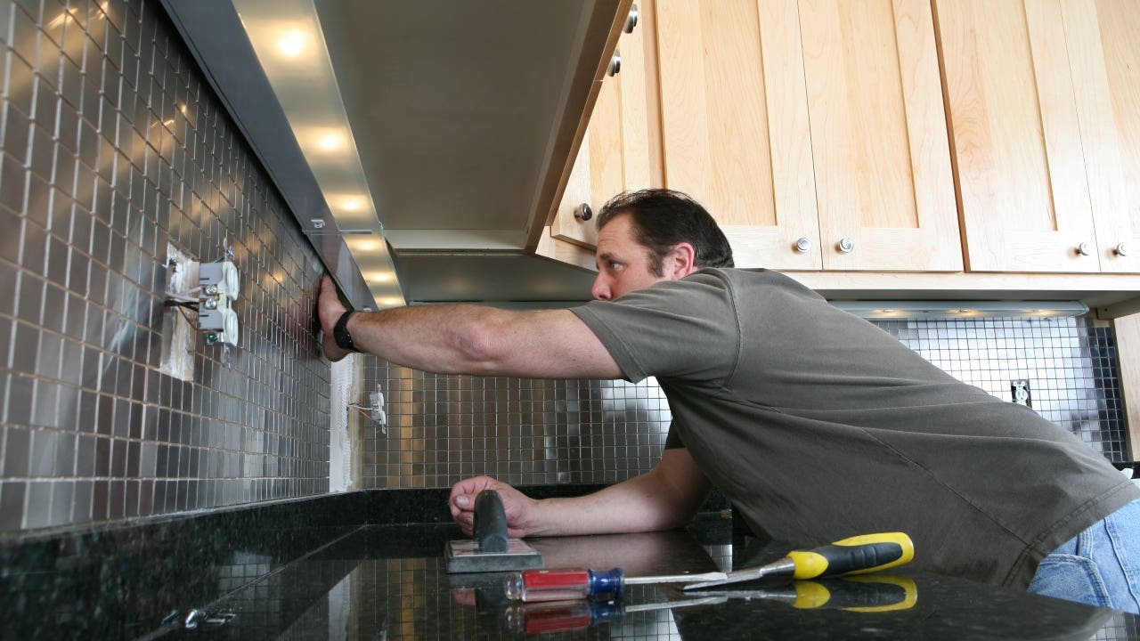A contractor installs backsplash in a kitchen