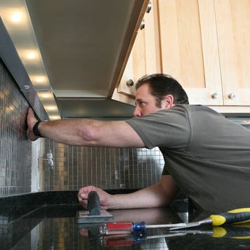 A contractor installs backsplash in a kitchen