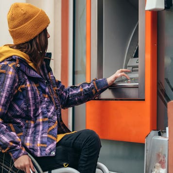 woman in a wheelchair using atm to withdraw money
