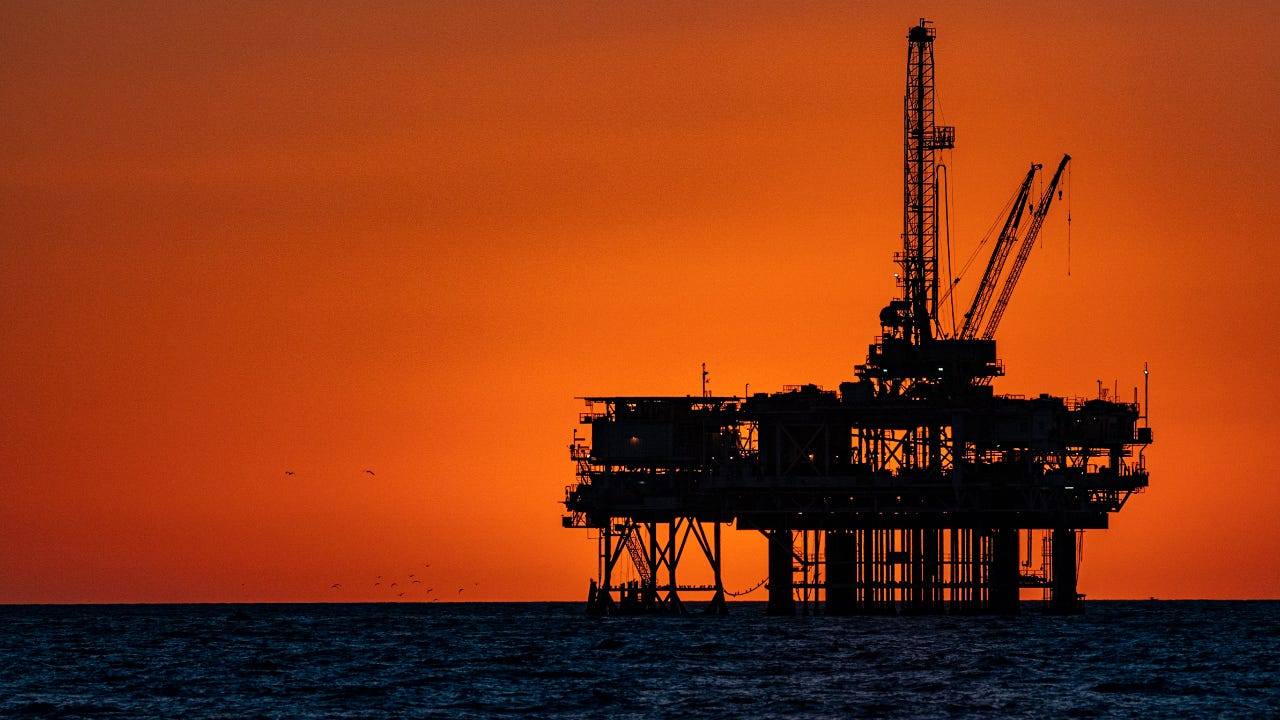 A silhouette of an offshore oil rig at dusk