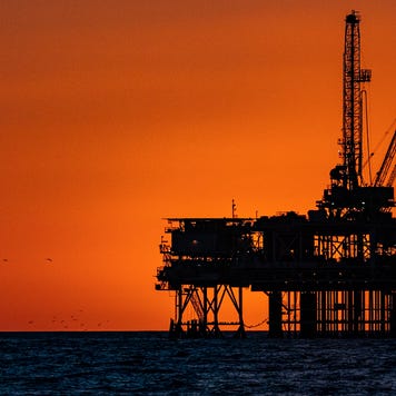A silhouette of an offshore oil rig at dusk