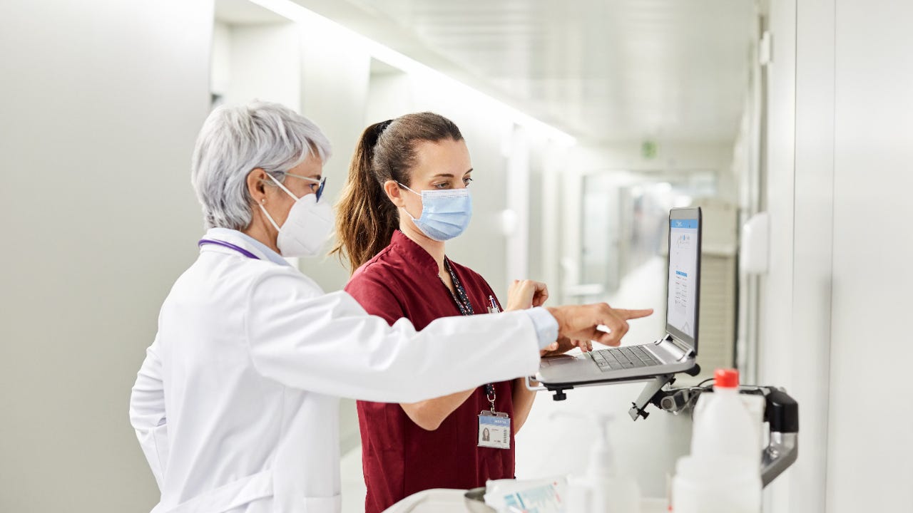 A doctor and nurse consult in front of a computer